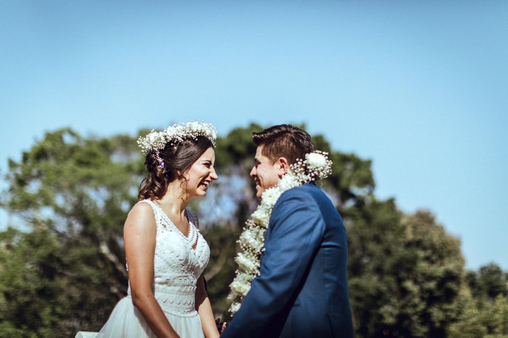 A joyful wedding moment shared between a couple wearing traditional wedding attire outdoors.