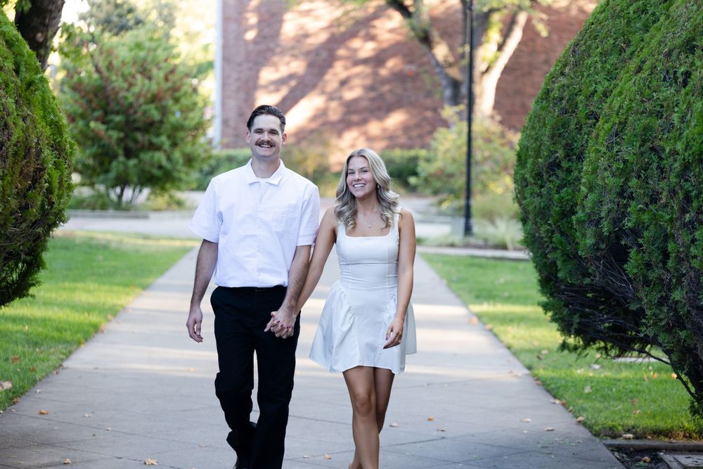 Engagement session at Chico State in Chico, California with brick building in background and green bushes in foreground