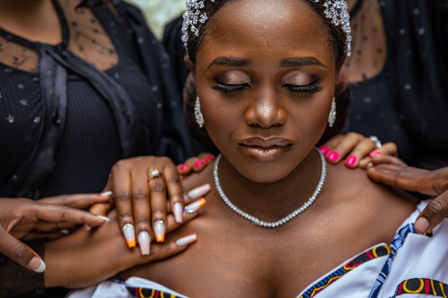 Woman wearing jewelry and makeup with hands on her shoulders.
