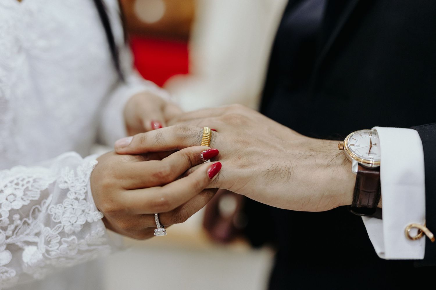 Close-up of hands exchanging wedding rings during a traditional ceremony.