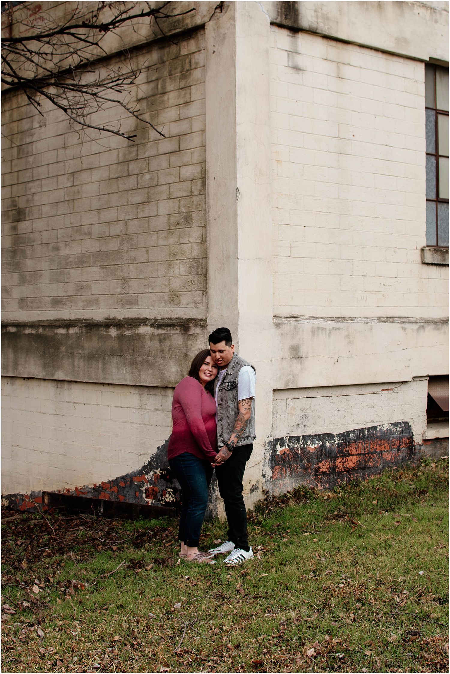 Couple enjoying intimate moment against white brick building wall in urban setting.