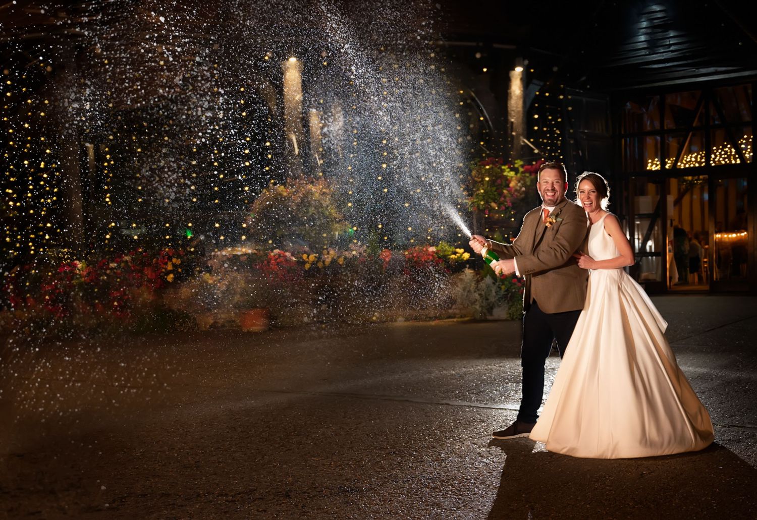 Newlyweds pose with sparklers creating magical nighttime wedding photo.