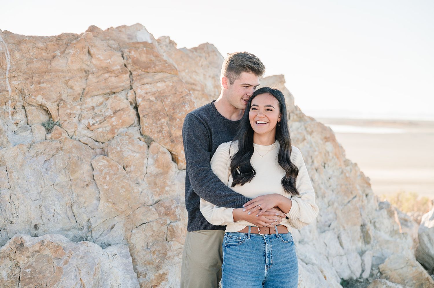 Couple sharing intimate moment against rocky desert backdrop in casual attire.