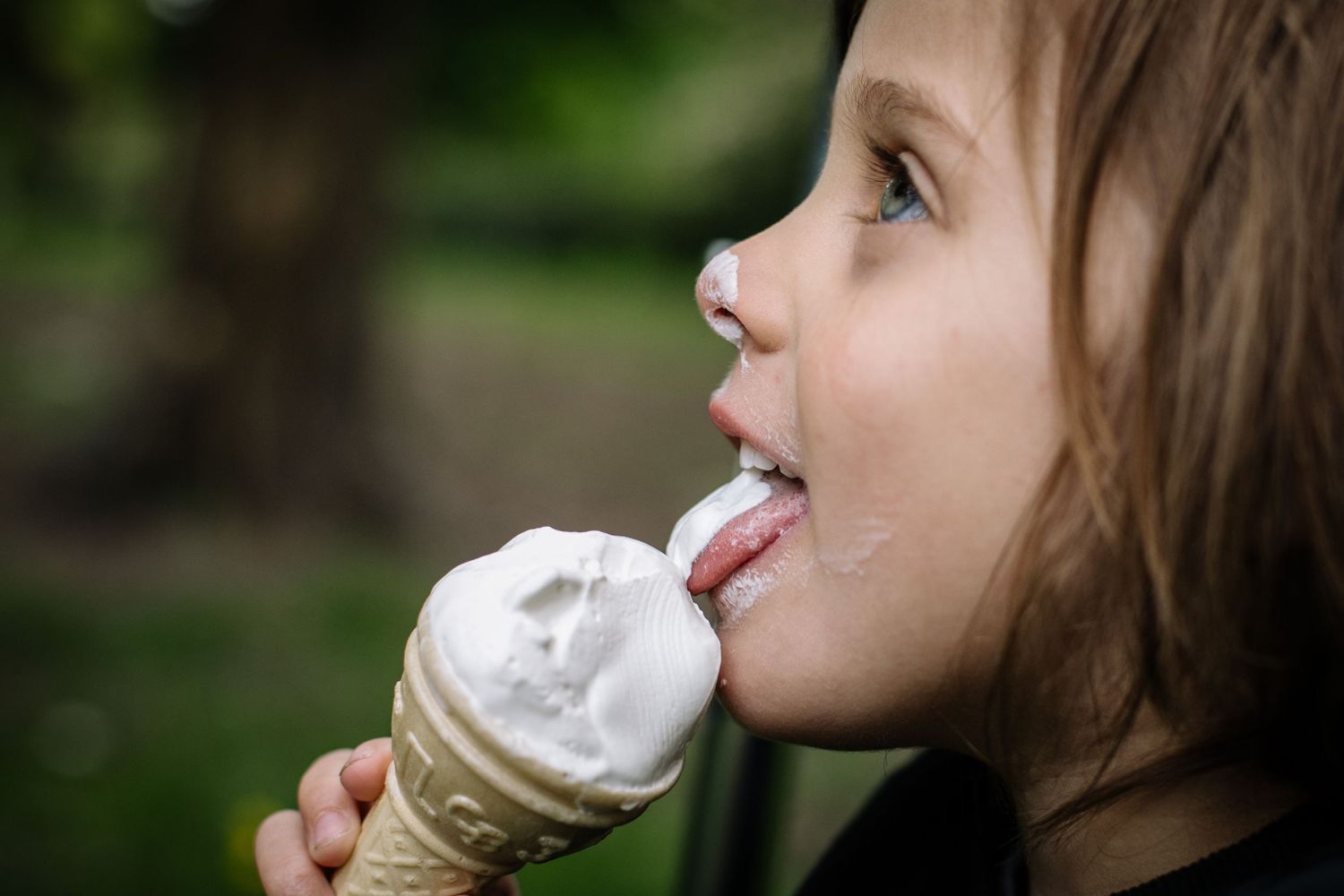 Close-up of someone enjoying a vanilla ice cream cone on a summer day.