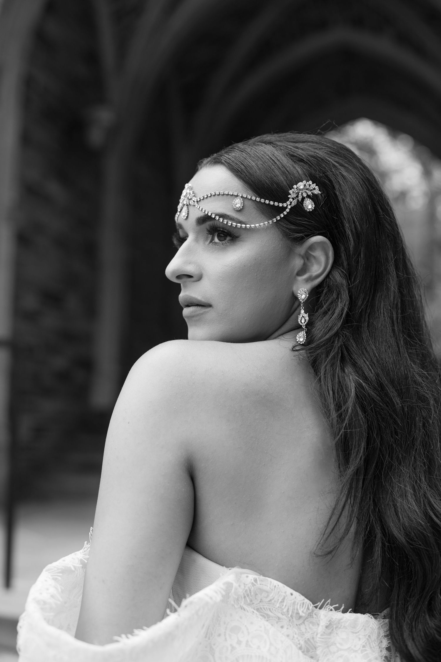Black and white profile portrait showcasing intricate headpiece jewelry and bare shoulders.