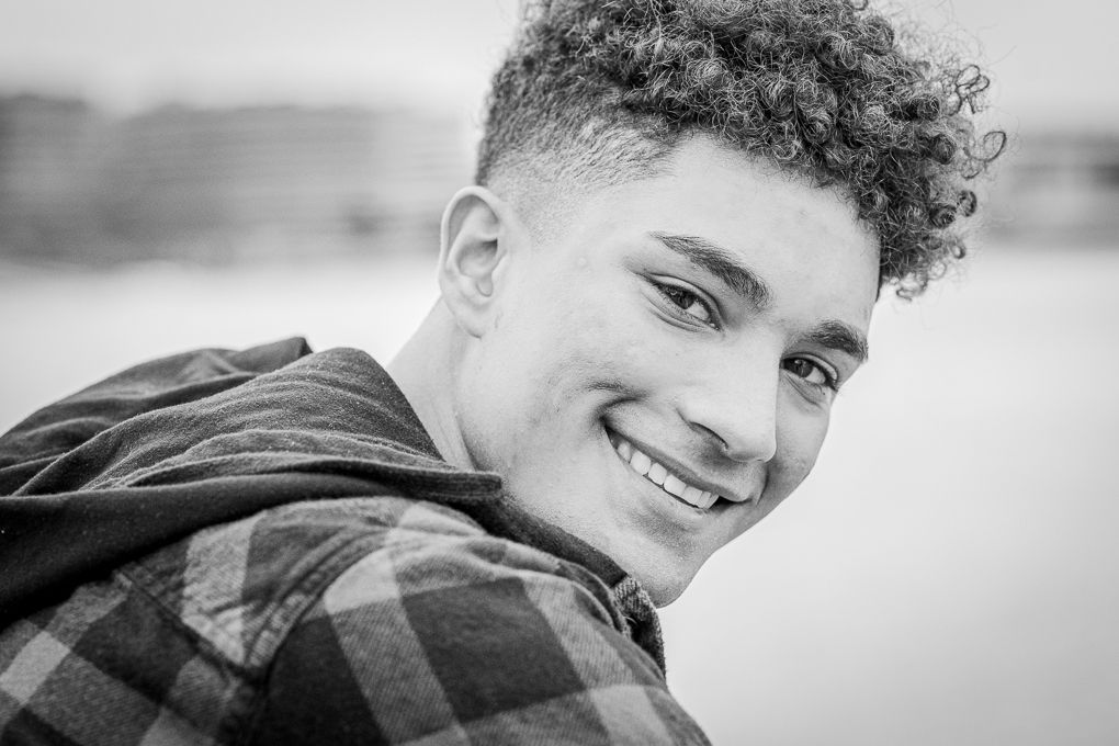 A high school senior rests his arms against a railing on the Georgetown waterfront and looks over his shoulder.