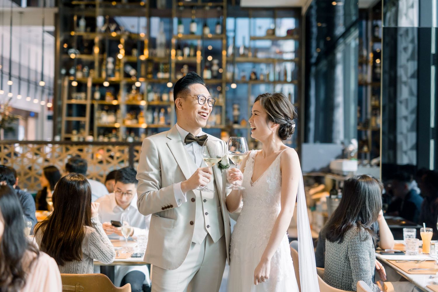 Elegant wedding celebration in a modern restaurant with glass walls and warm lighting.