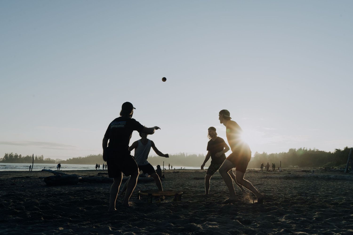 Silhouettes of people playing with a ball on a beach at sunset.