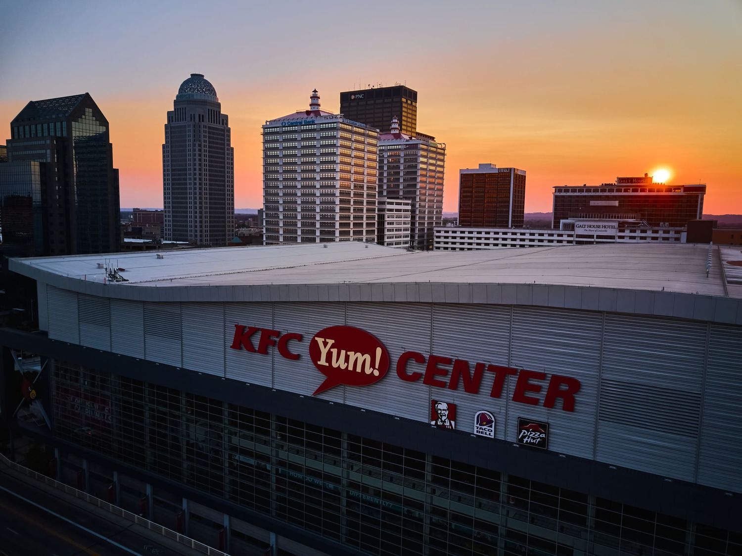 Cincinnati skyline at sunset with dramatic orange sky behind downtown buildings.