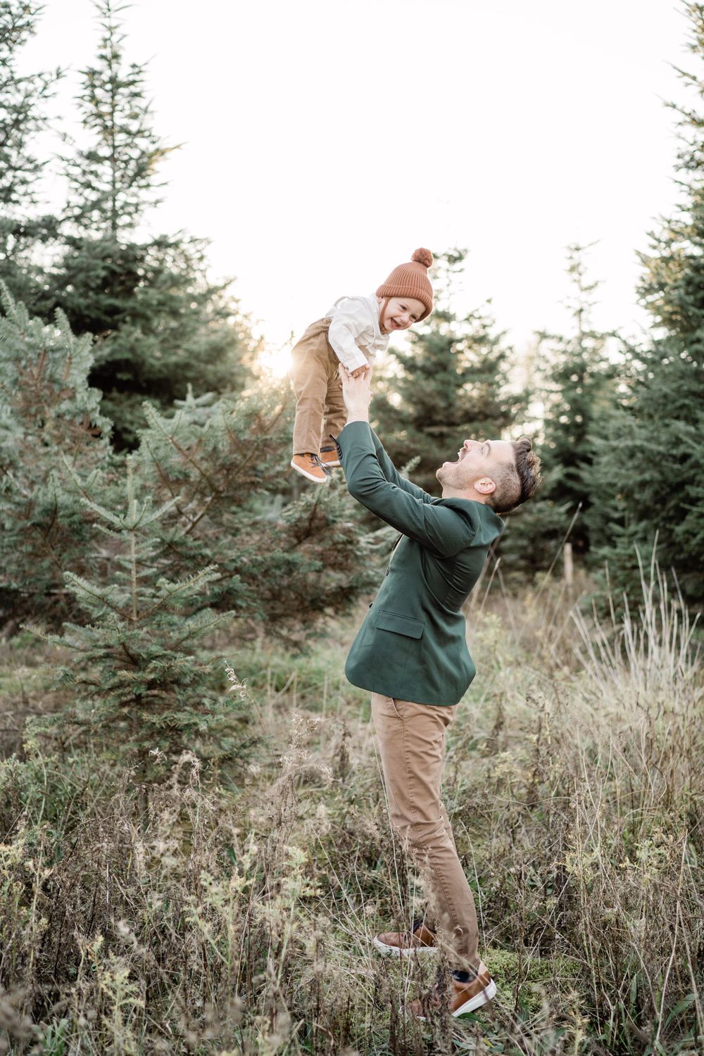 father tosses sun playing at sunset in the forest tree farm photos