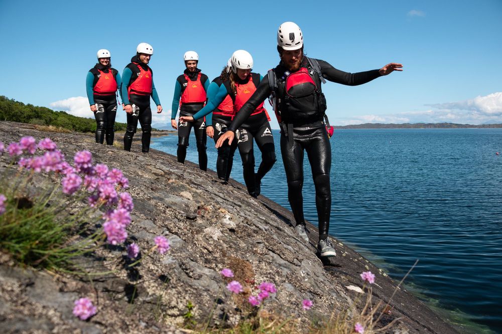 Seatrek Scotland guide leads group along coastal rocks next to sea