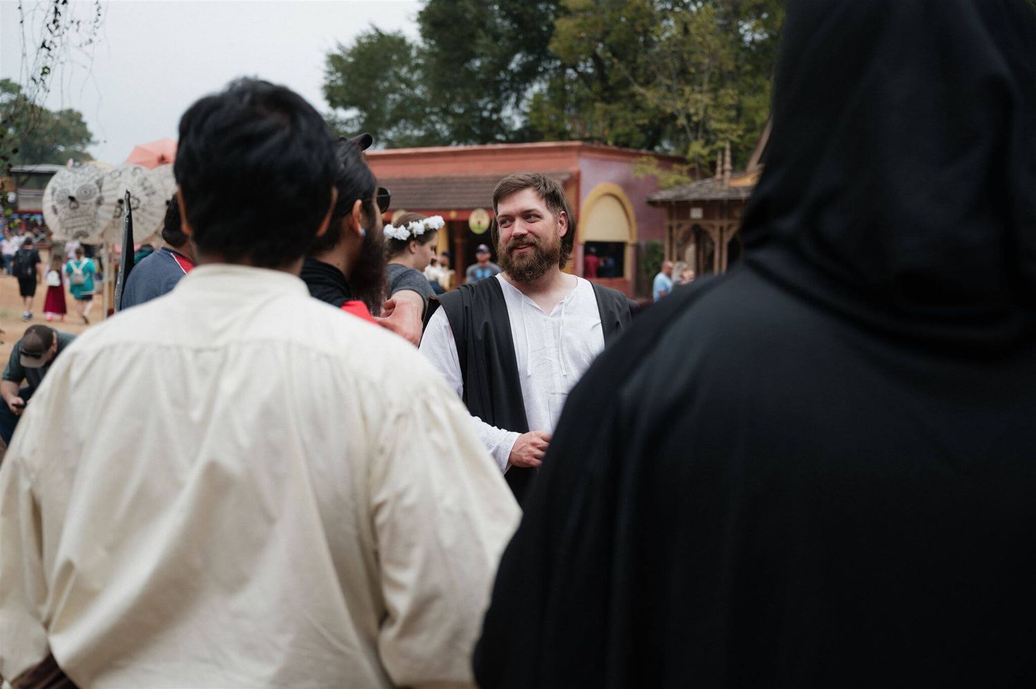 Crowd of attendees in period costumes conversing at a renaissance fair.
