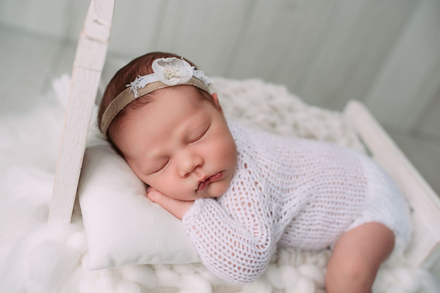 newborn baby sleeping in a little white bed during a session