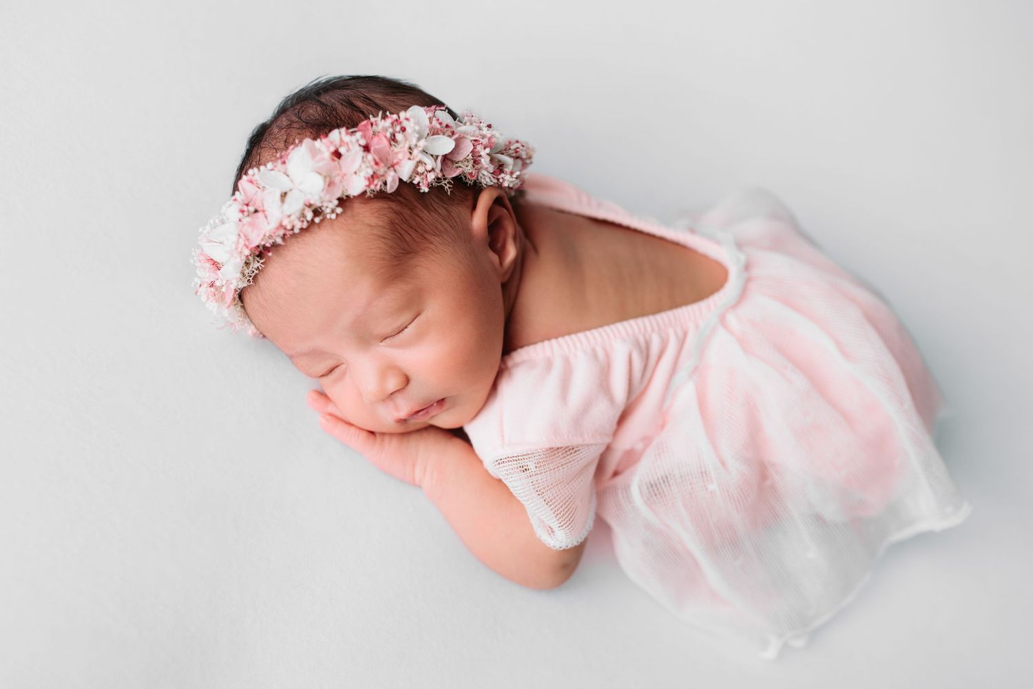 newborn baby girl in pink dress during her newborn photo shoot