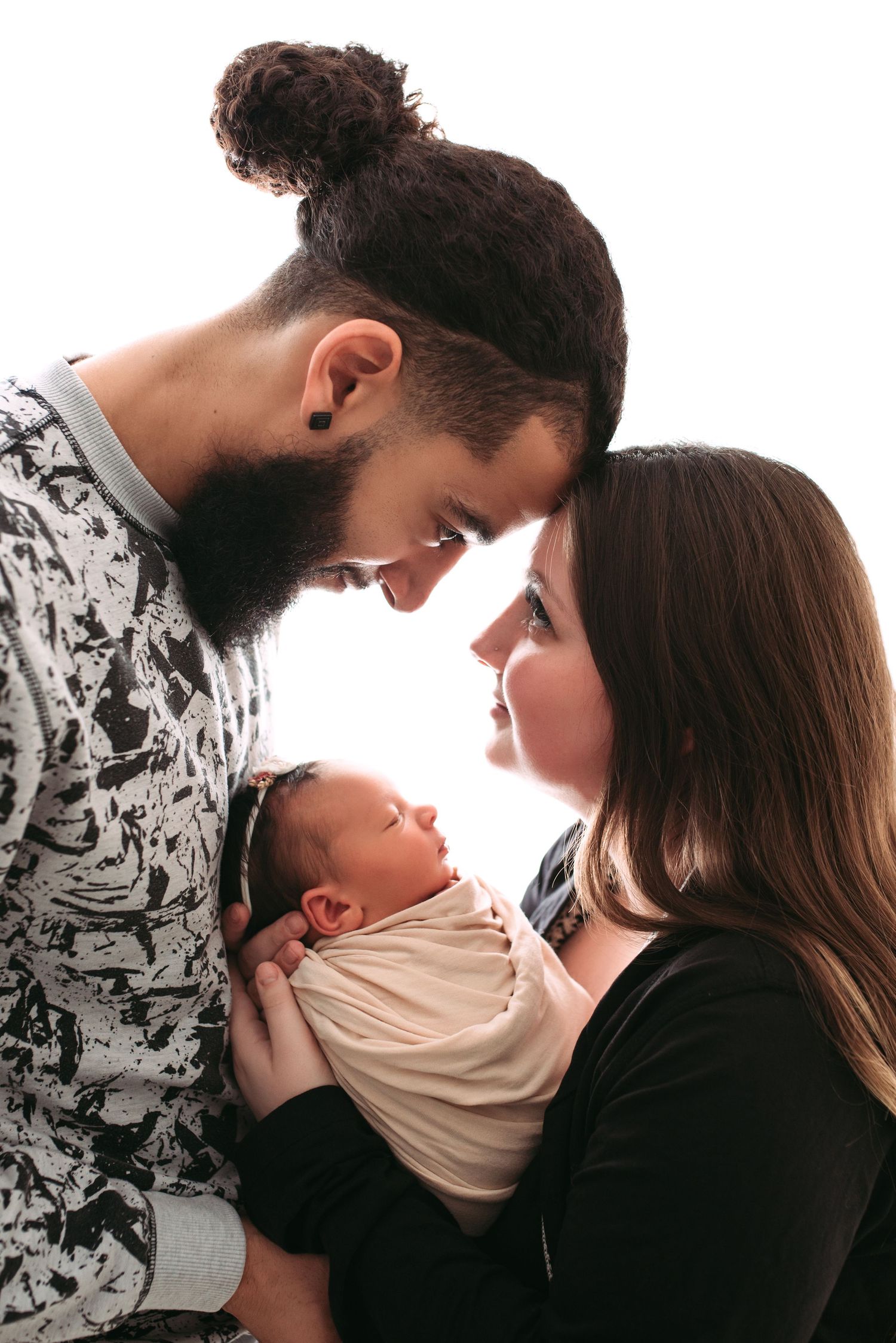parents holding newborn baby in their hands and looking at each other with love