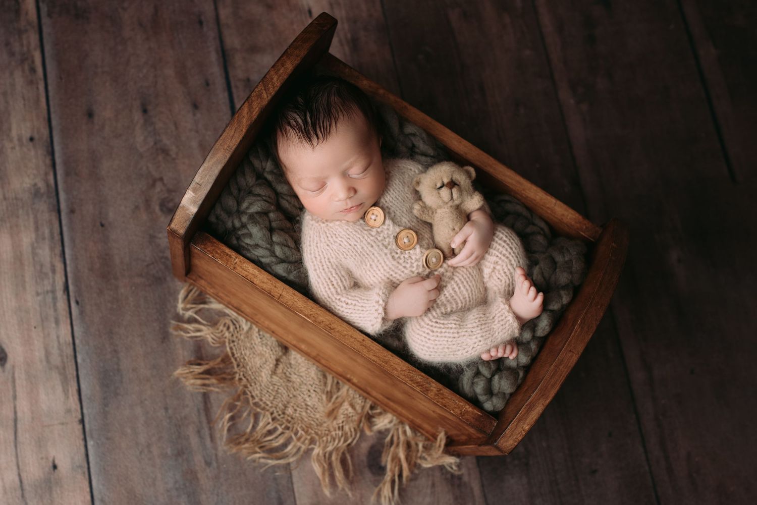 Newborn baby sleeping in his bed with small teddy in his hand