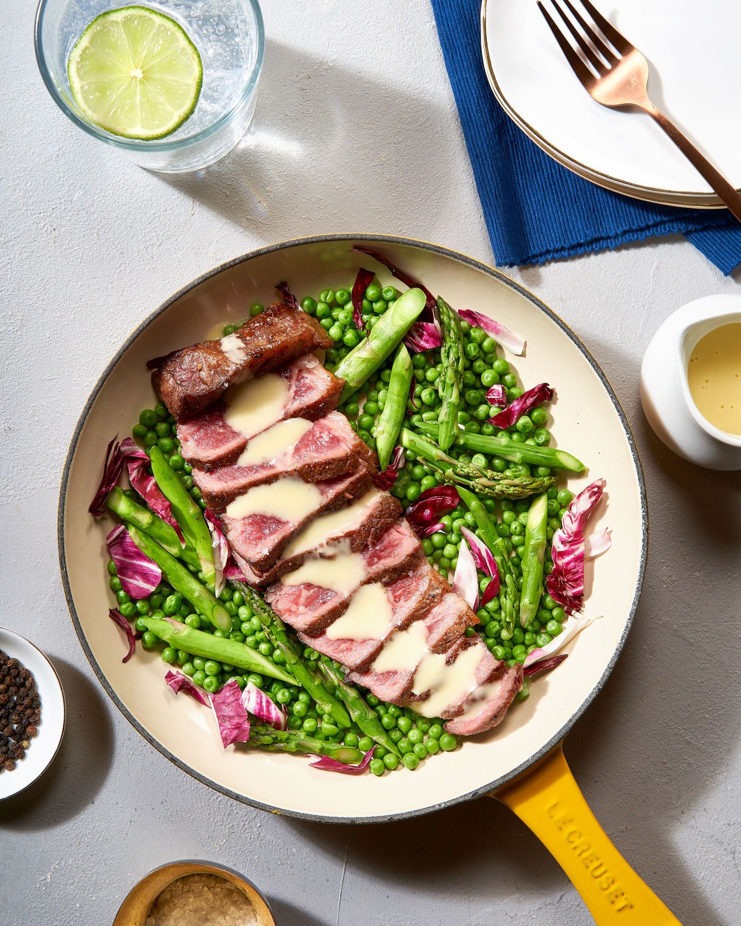 Seared duck breast sliced and served with green vegetables and purple garnish on a white ceramic plate.