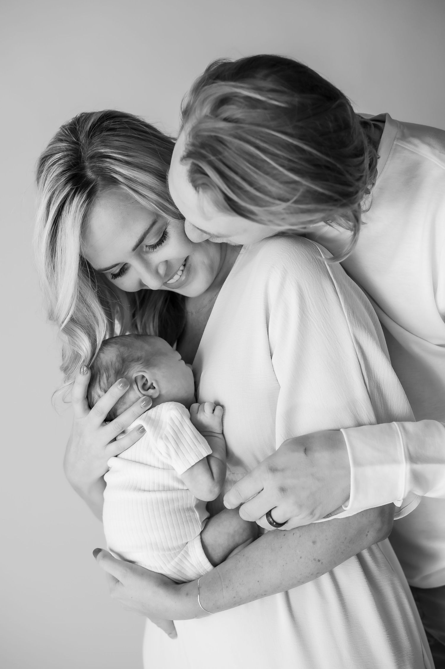 Black and white photo of two women lovingly cradling a newborn baby.