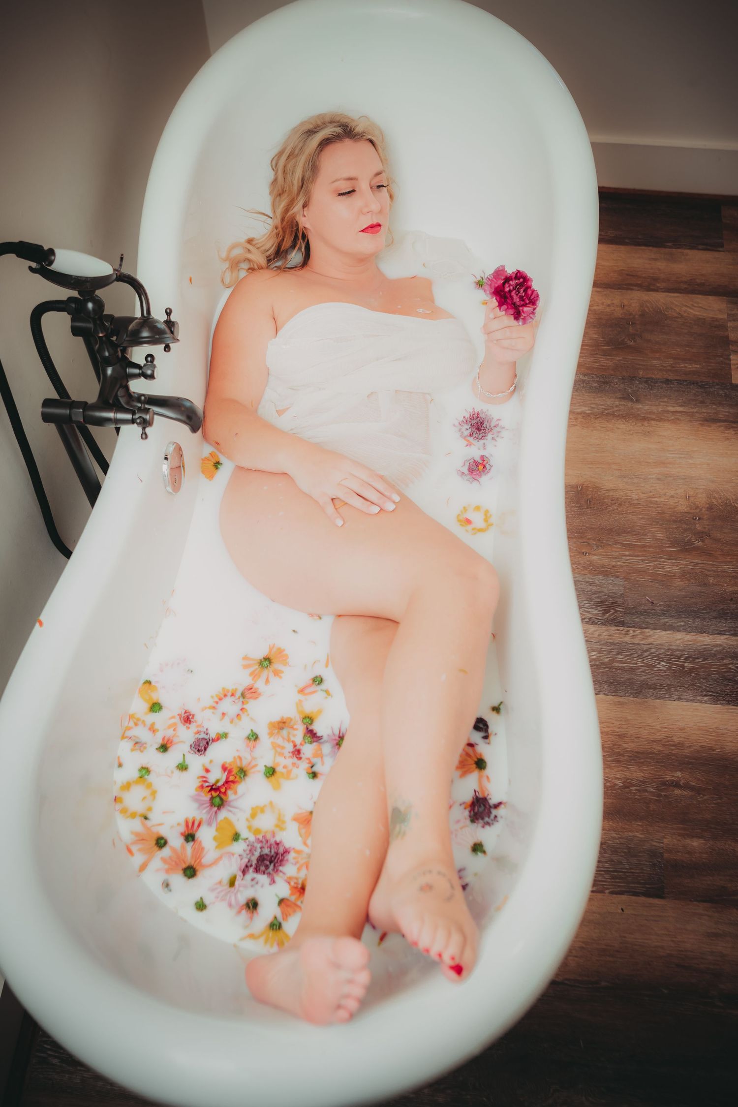 Southern Utah boudoir photographer located in St. George helping celebrate everyBODY. Woman in milk bath with flowers