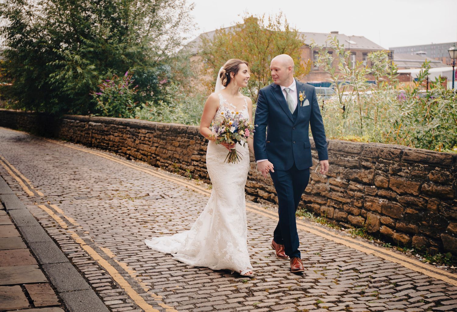 bride and groom walk the cobbled steet outside kelham island museum sheffield yorkshire wedding photography