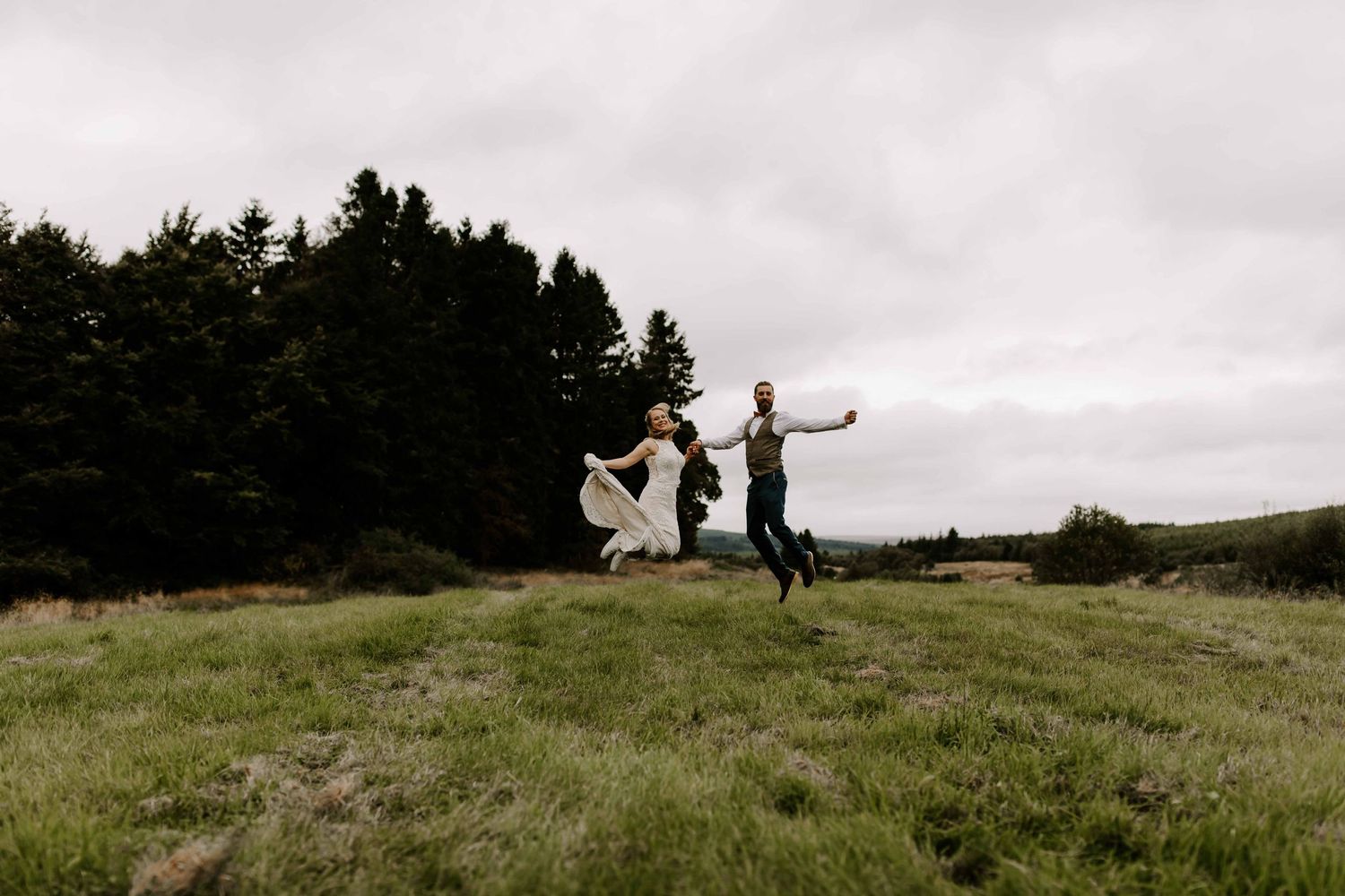 The Comb in Northumberland with wedding couple jumping, in a field