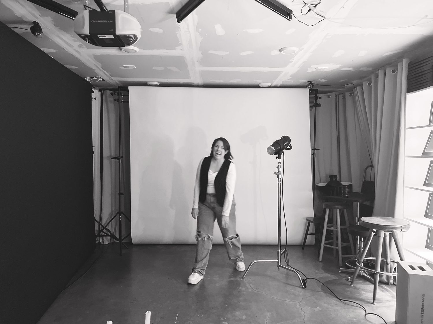 Photography studio setup with white backdrop, lighting equipment and hardwood floors.
