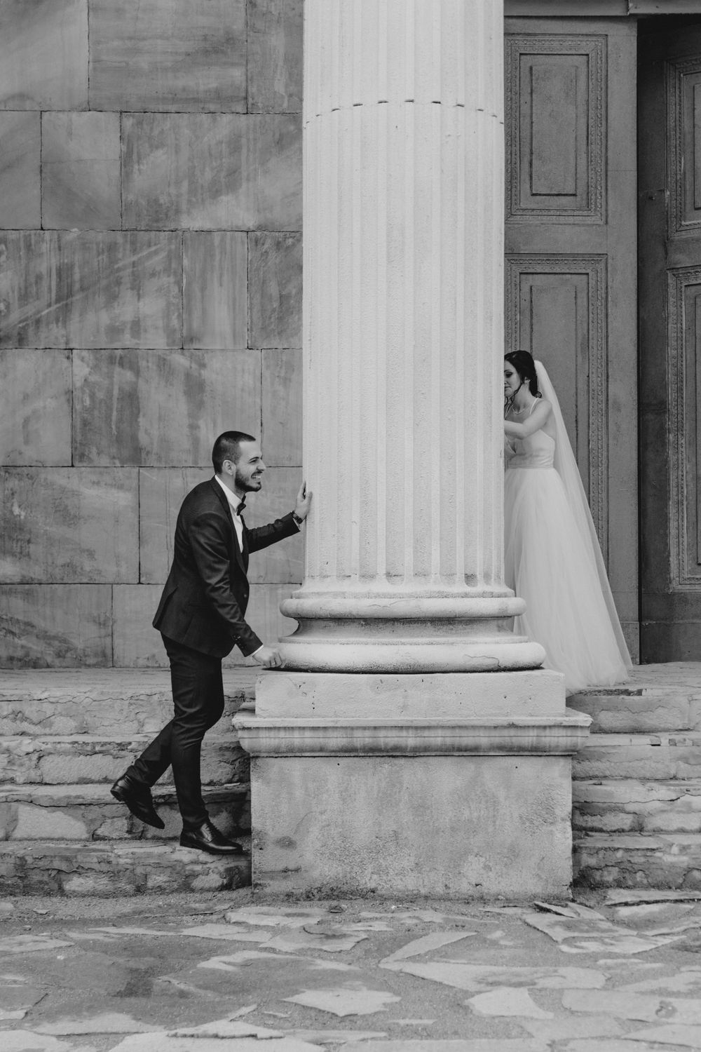 сватбена фотосесия на младоженци, които се крият един от друг зад колона