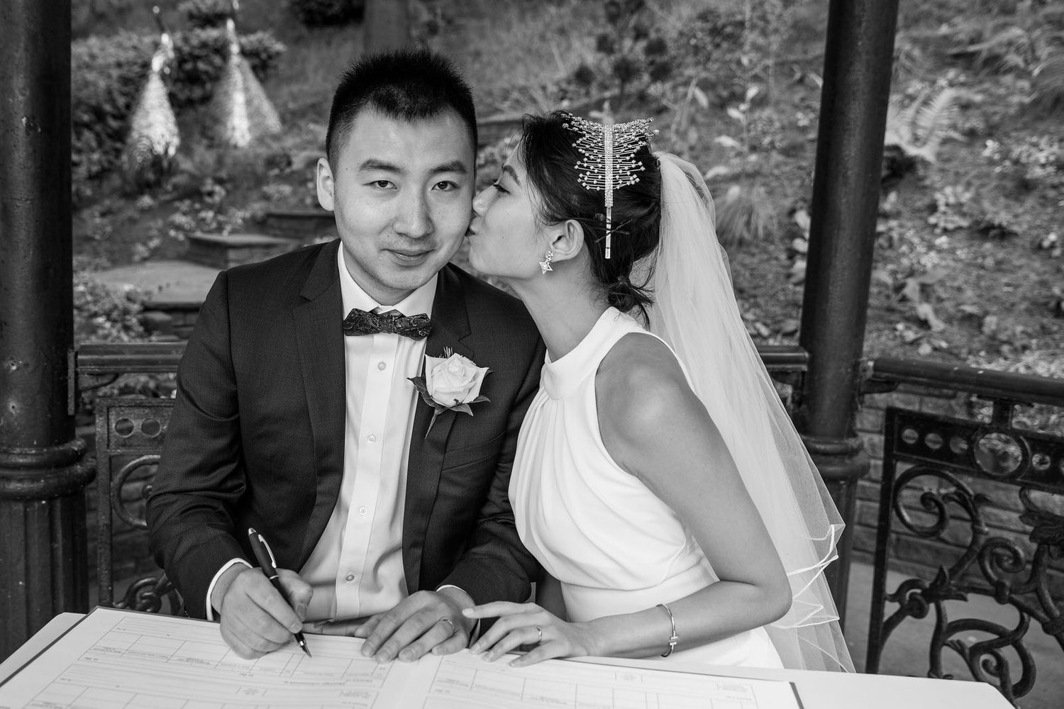 Chinese Bride & Groom kissing whilst signing wedding register