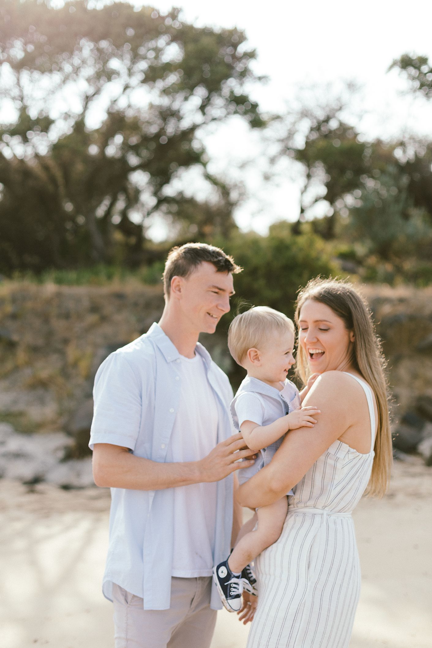 A family shares playful moments together on a sandy beach during golden hour.