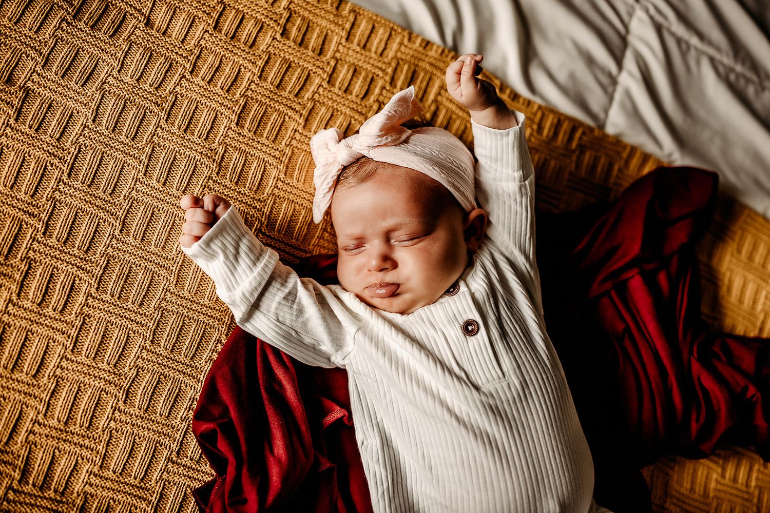 A newborn baby girl gives a good stretch after coming out of her swaddle.