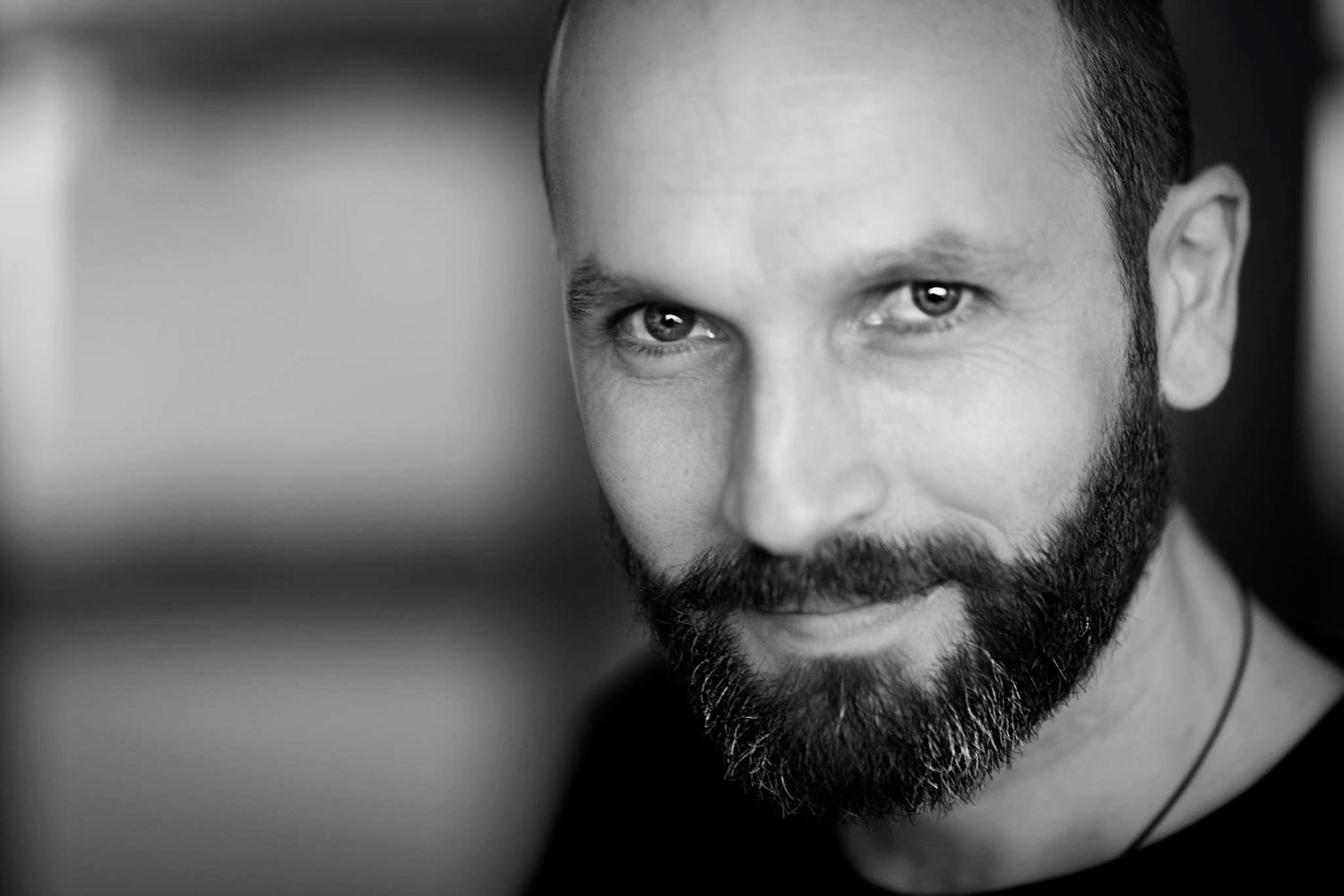 Close-up black and white portrait showing half of a bearded face in dramatic lighting.