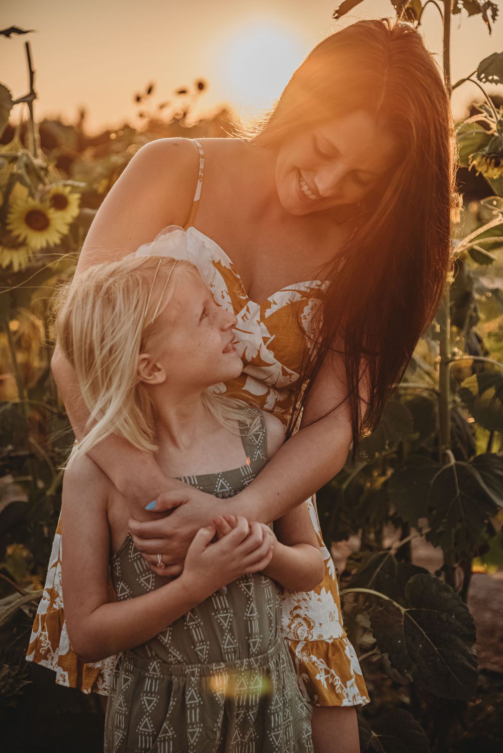 Joyful candid moment in a sunflower field at sunset with warm golden lighting.