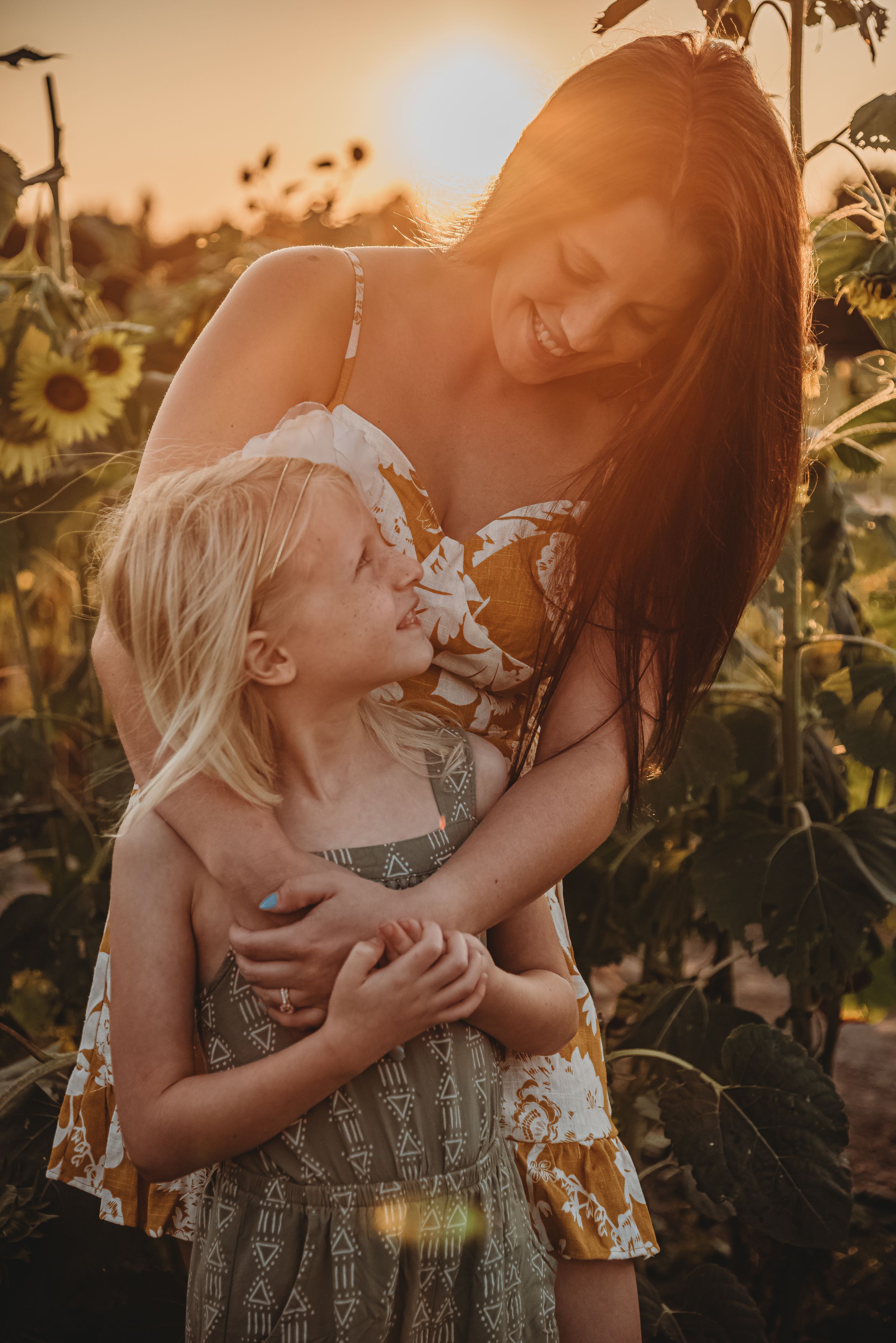 Joyful candid moment in a sunflower field at sunset with warm golden lighting.