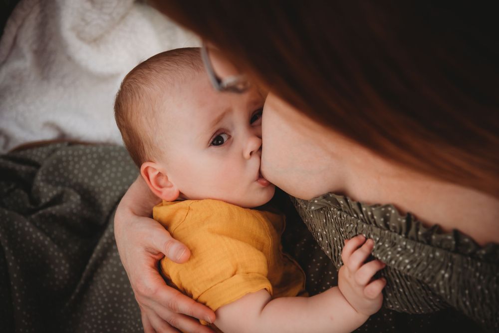 Tender moment captured between parent and infant in golden outfit.
