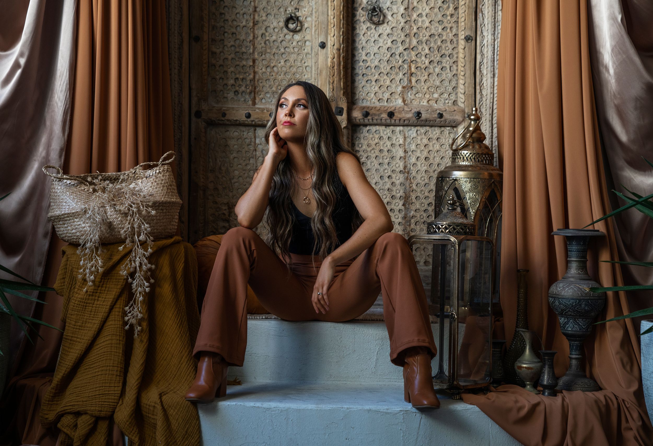 Artistic self-portrait on steps among vintage decor and drapery.