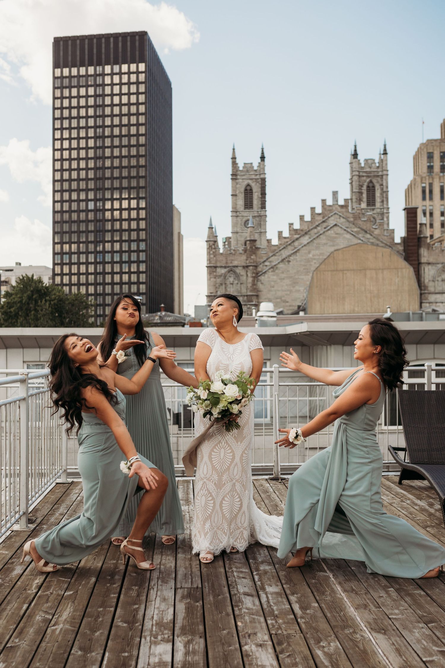 Fun bridal party photo shoot on rooftop with urban architecture and church spires in background.