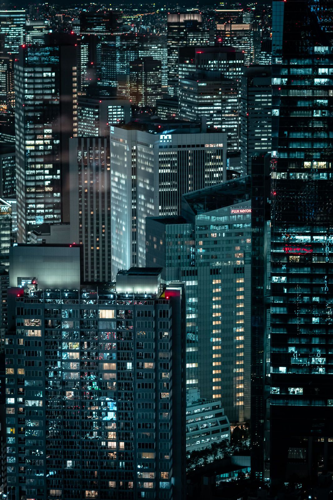 Modern office buildings illuminated at night creating a cyberpunk-style urban landscape.