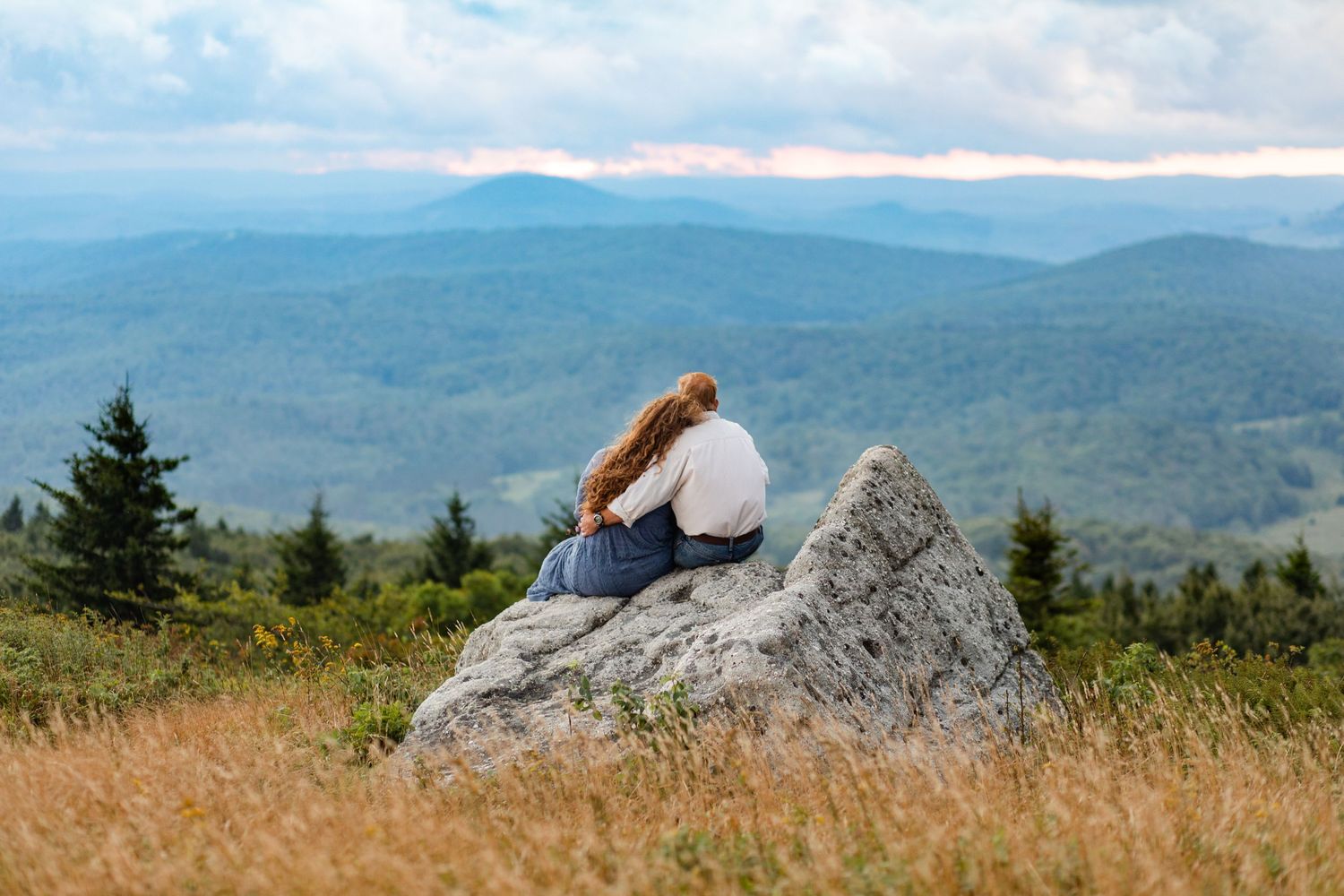 Panoramic mountain landscape with rolling hills and distant peaks under cloudy skies.