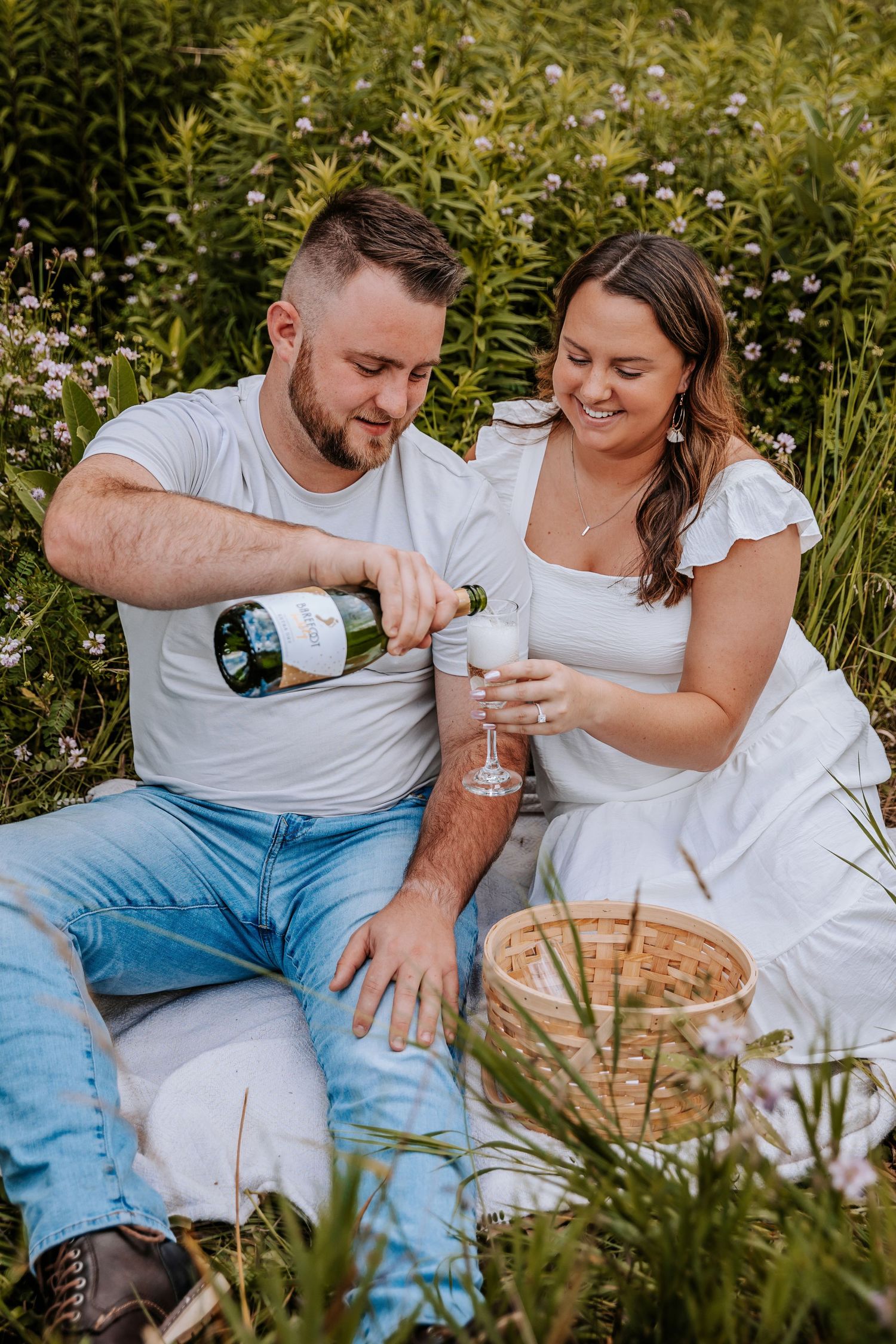 Couple enjoying wine picnic outdoors in natural garden setting.