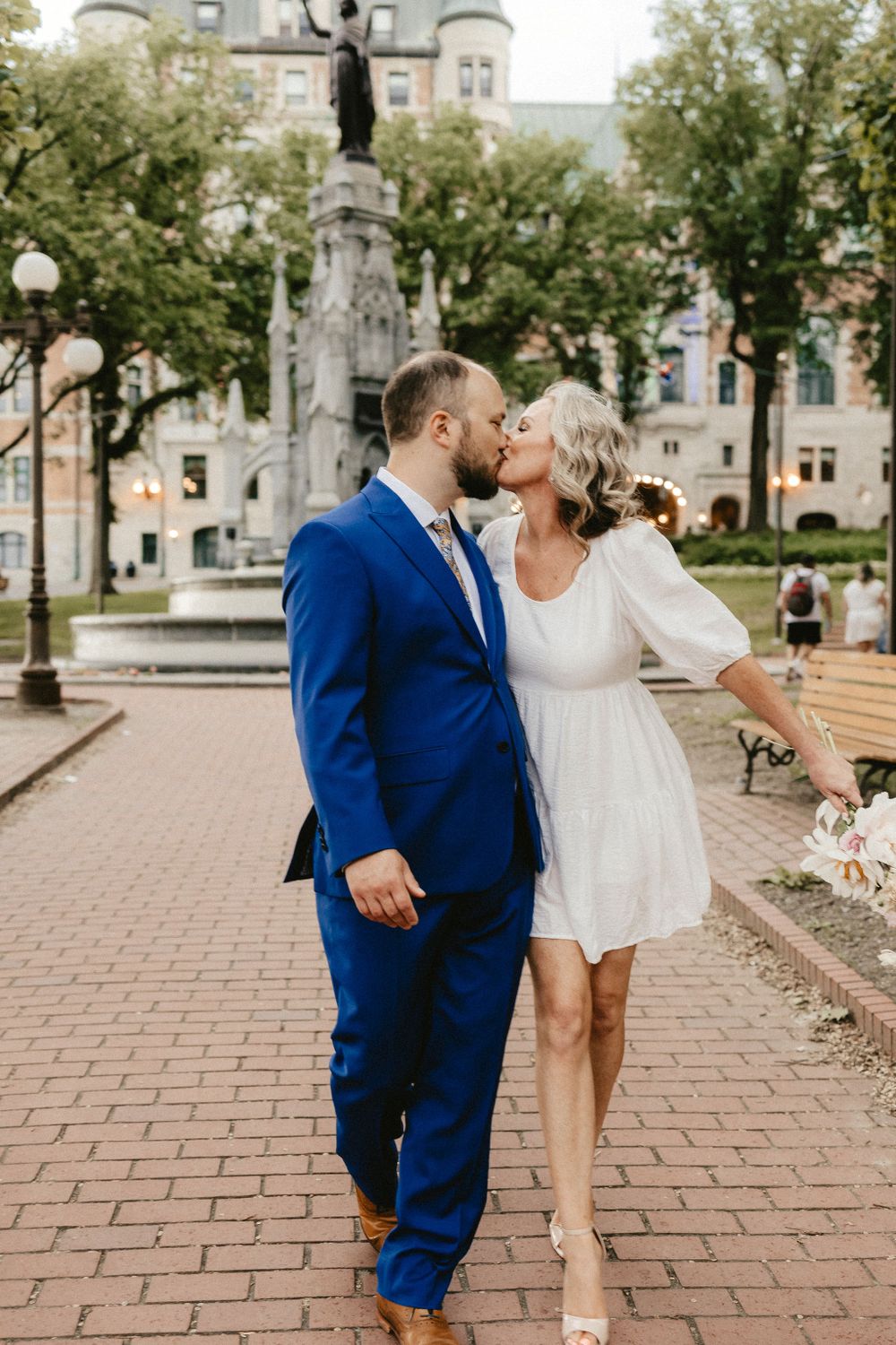 A couple shares a romantic moment in front of a historic building with gothic architecture.