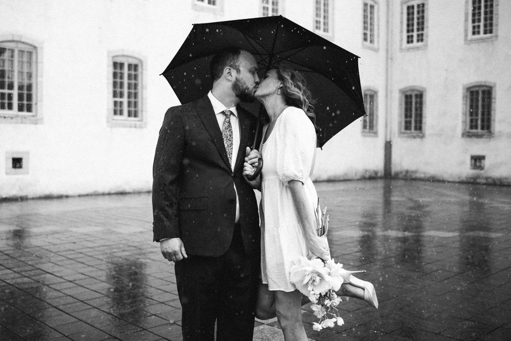A romantic black and white photo of a couple sharing an umbrella in the rain.
