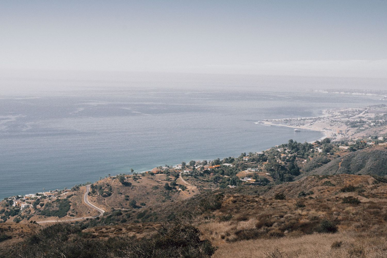 Panoramic coastal landscape view showing rolling hills and ocean in the distance.