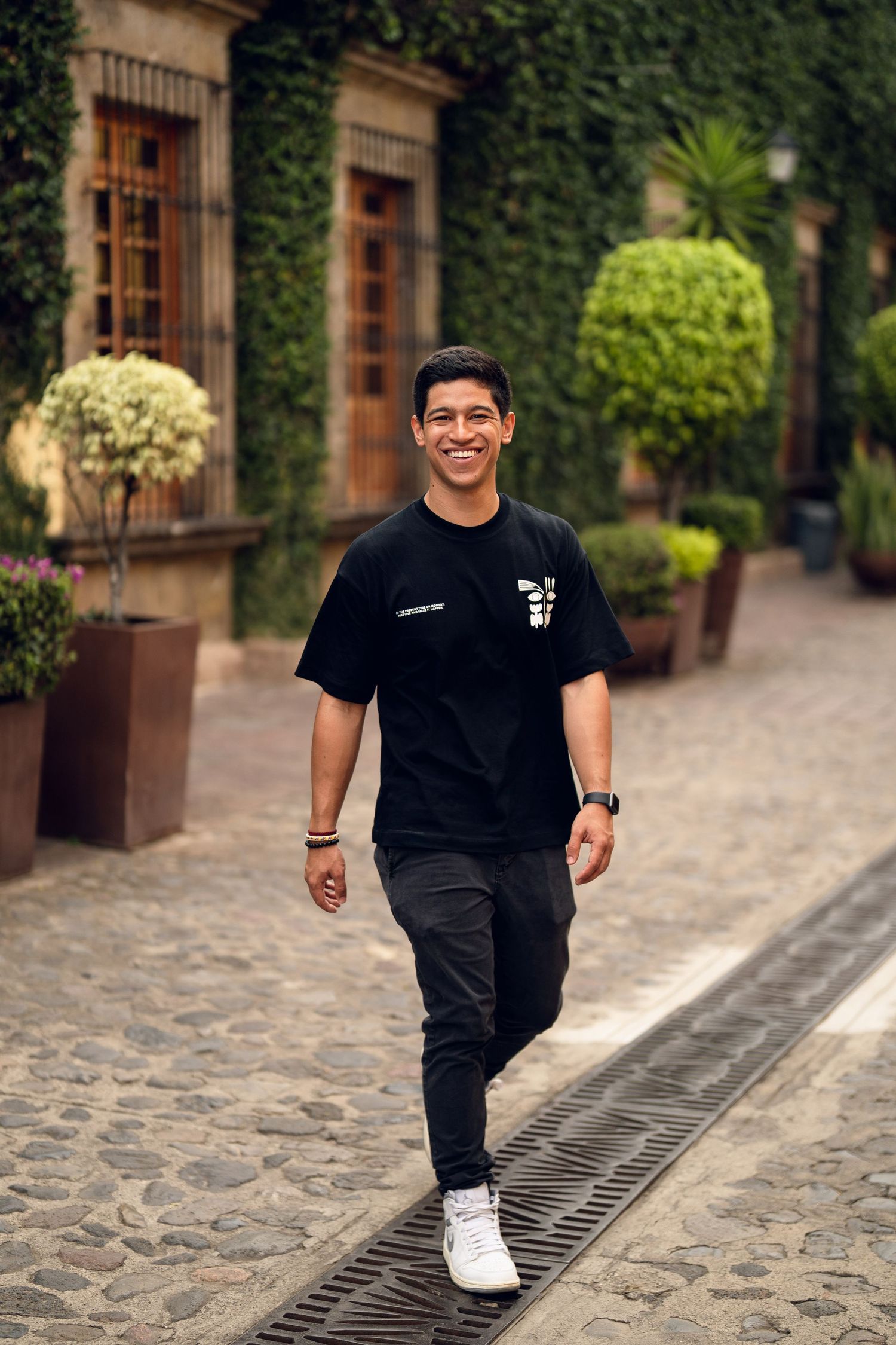 Five sequential photos showing a person in all black attire walking on a cobblestone path near brick buildings.