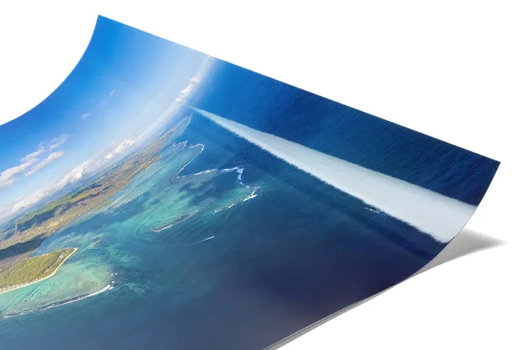 Curled corner of aerial coastal photograph showing turquoise waters and shoreline.