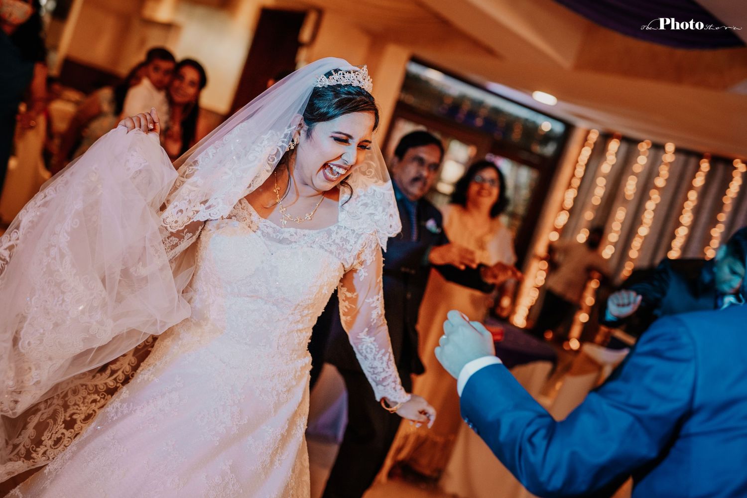 Wedding celebration with dancing couples under warm lighting and string light decorations.