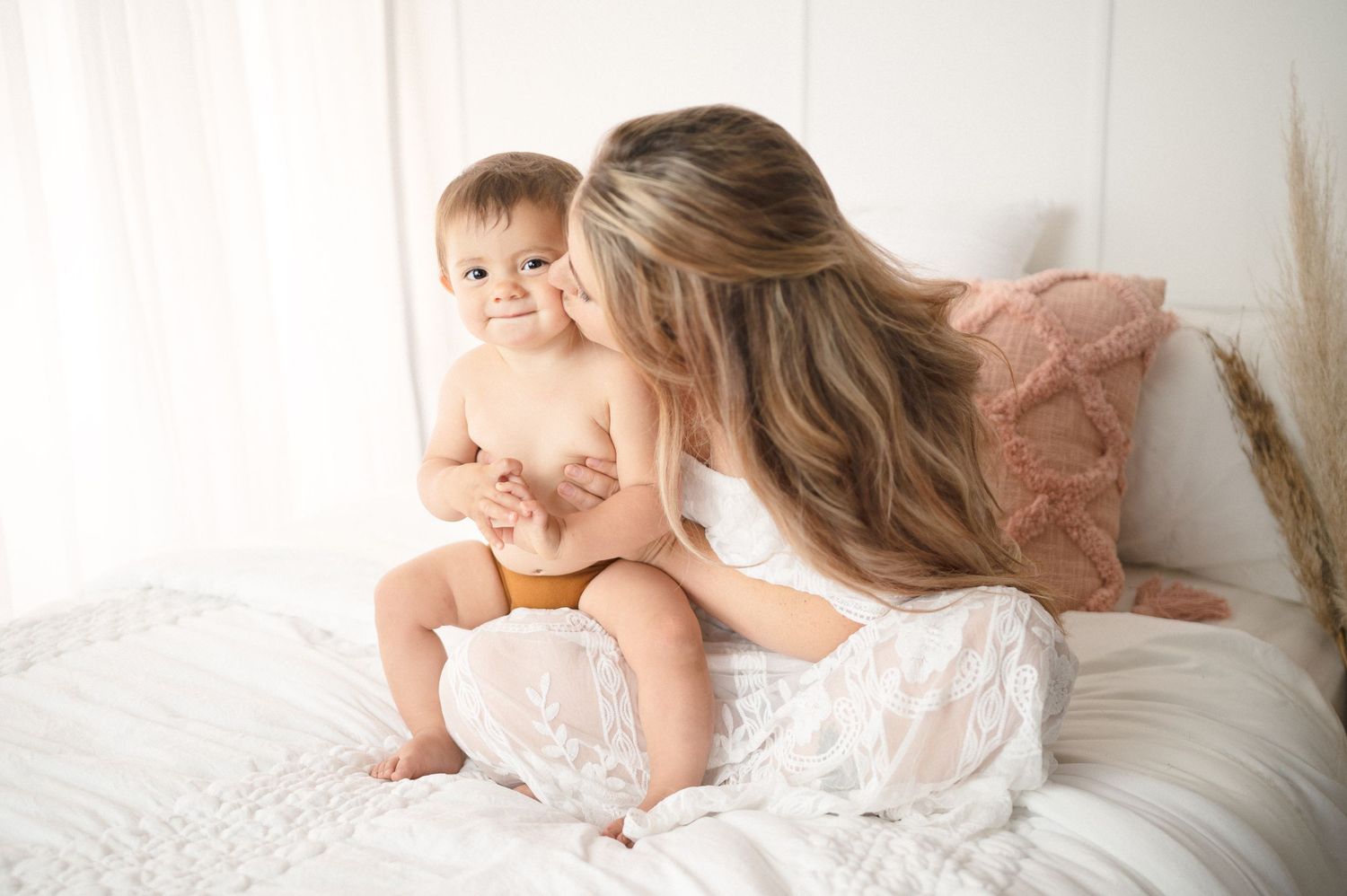Intimate lifestyle portrait of mother and baby relaxing together on bed.