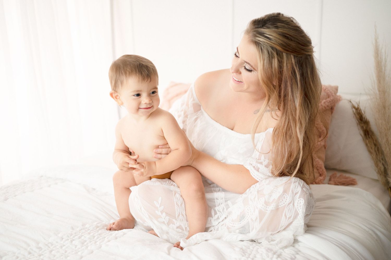 Sweet candid moment between mother and baby during relaxed bedroom photo session.