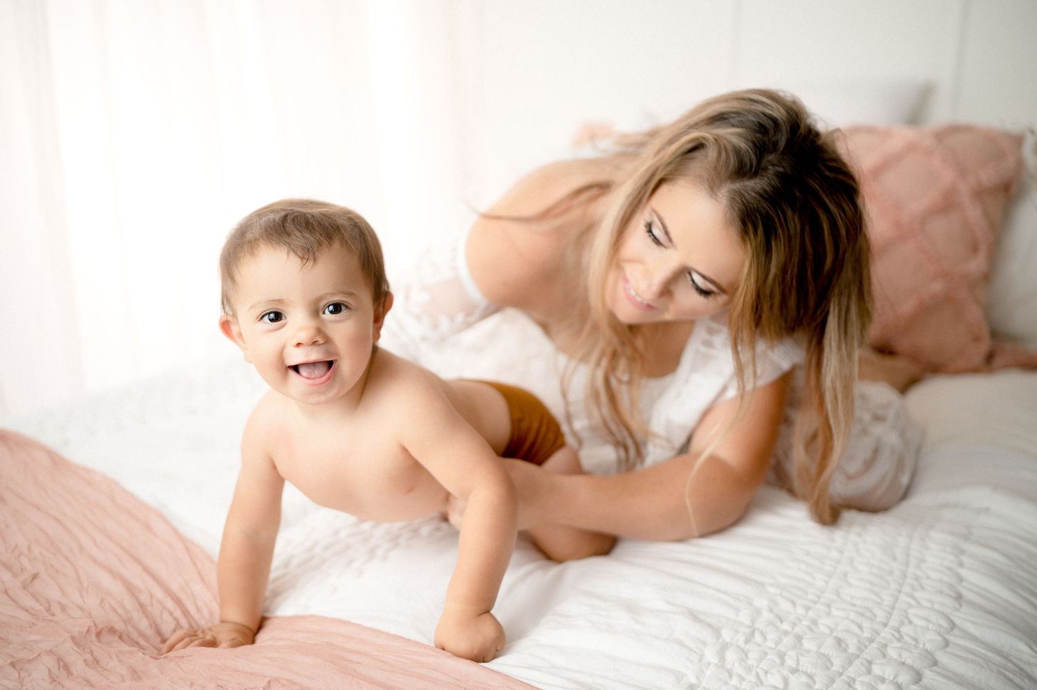 Mother and crawling baby share joyful moment during casual photo session.