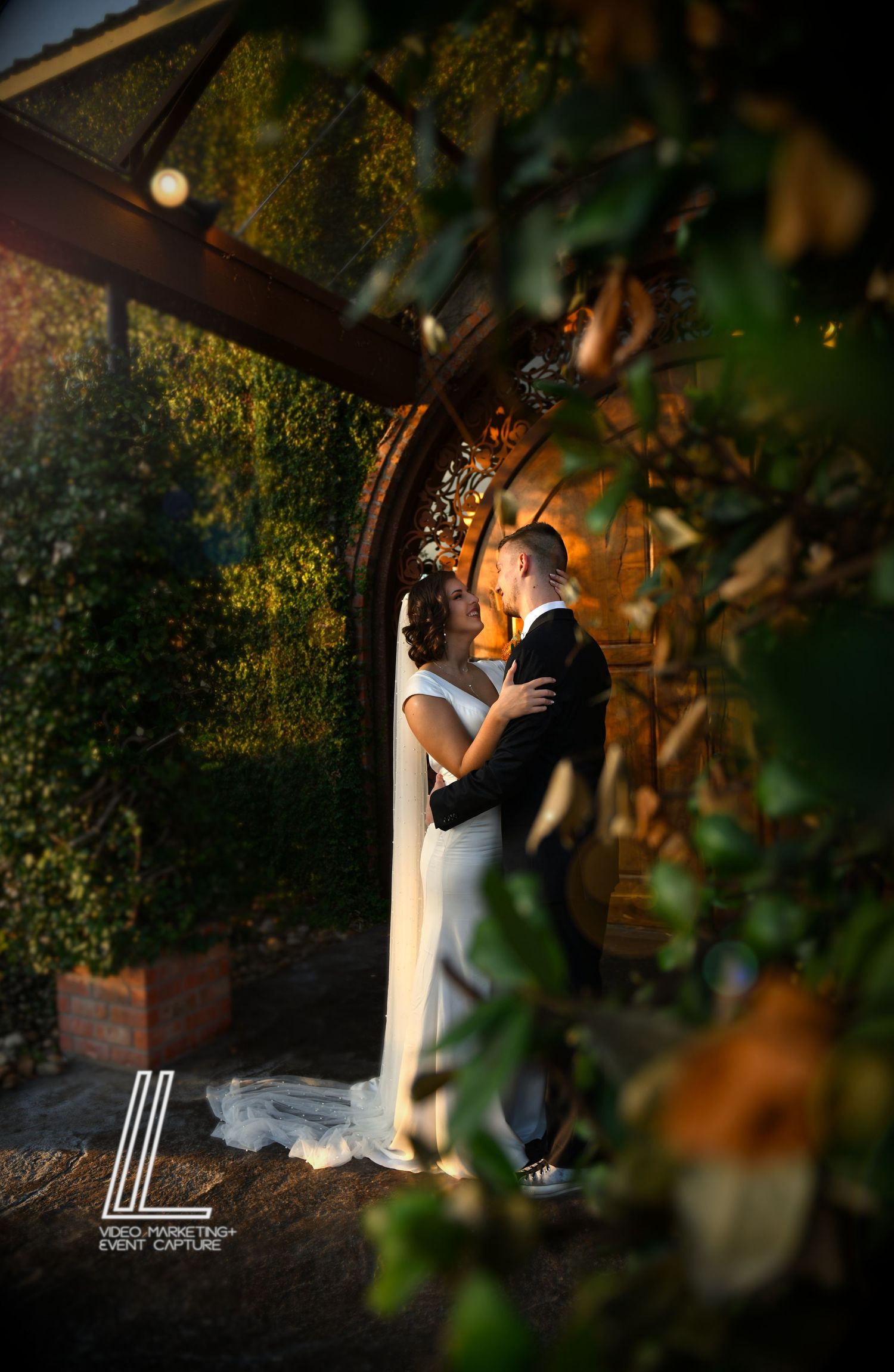 Beautiful Dramatic Bride and Groom Night Portrait Wooden Doors Night Lights Foliage