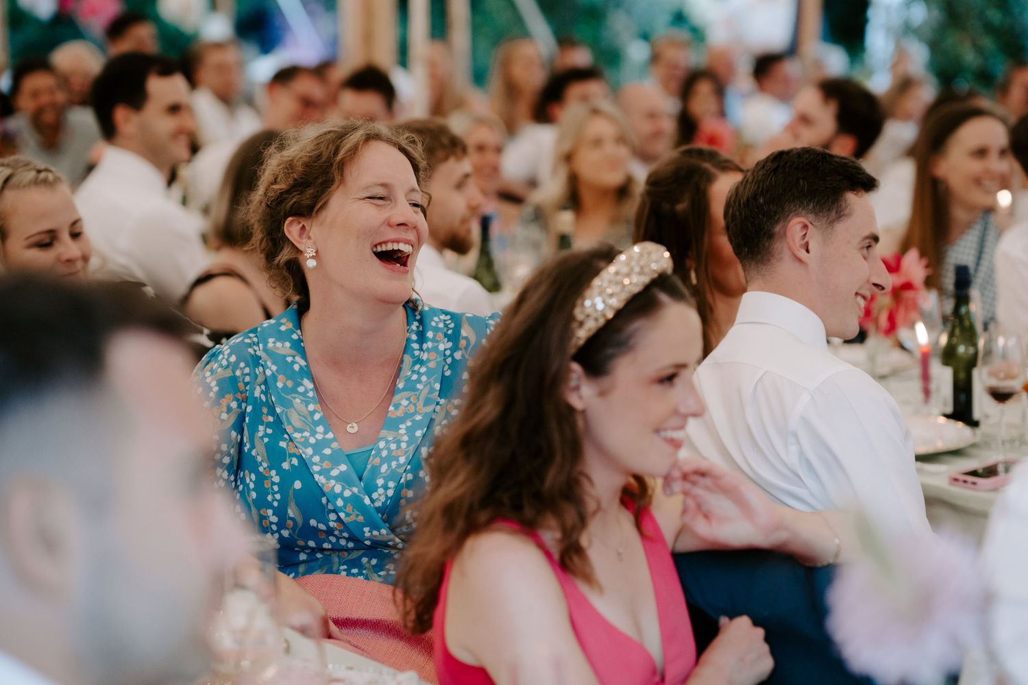 wedding guest laughing at father of the bride speech at wedding in marquee in islip in Oxfordshire